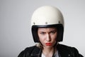 Portrait of biker young woman, with serious face, wearing white helmet, with red lips. Studio background. Royalty Free Stock Photo