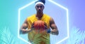 Portrait of biracial basketball player holding ball by illuminated hexagon and plants Royalty Free Stock Photo