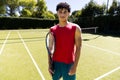 Portrait of biracial confident young man holding tennis racket while standing in court Royalty Free Stock Photo