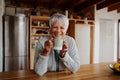 Portrait of retired biracial elderly female leaning on kitchen counter smiling at camera. Happy pensioner Royalty Free Stock Photo