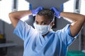 Portrait of biracial female surgeon wearing scrubs and face mask in operating theatre Royalty Free Stock Photo