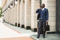 portrait of black african american businessman in suit outdoors with briefcase in hand standing and talking on the phone Royalty Free Stock Photo