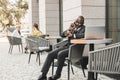 Portrait of a black African American businessman in a suit sitting in a city cafe outdoors and talking on the phone. Royalty Free Stock Photo