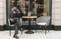 Portrait of a black African American businessman in a suit sitting in a city cafe outdoors and talking on the phone. Royalty Free Stock Photo