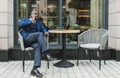 Portrait of a black African American businessman in a suit sitting in a city cafe outdoors and talking on the phone. Royalty Free Stock Photo