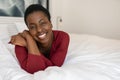 Portrait Black African woman laying on bed, smiling looking into camera