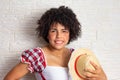 Black brazilian woman with curly hair holding straw hat dressed with typical plaid shirt. Festa Junina in Brazil,