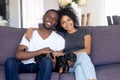 Portrait of black couple with cute dog relaxing on couch