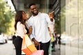Portrait of black couple with shopping bags pointing at mall Royalty Free Stock Photo