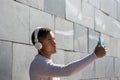 Portrait of black latin guy with headphones taking a selfie on the street with his cell phone Royalty Free Stock Photo