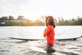 Portrait of black long-haired teen boy with surfboard ready for surfing with sunset backlight. He walking in Indian ocean waves. Royalty Free Stock Photo