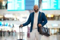 Portrait of black man, airport and smile with luggage and flight schedule display for business trip. Happiness, travel Royalty Free Stock Photo