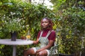 Black non-binary person sitting in an outdoor cafe