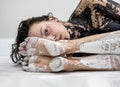 Portrait of a black painted sexy girl behind the feet of a white painted woman in the studio. Creative expressive abstract body