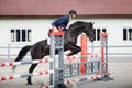 Black stallion horse and handsome man rider jumping obstacle during showjumping competition