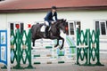 Black stallion horse and handsome man rider jumping obstacle during showjumping competition Royalty Free Stock Photo