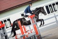 Black stallion horse and handsome man rider jumping obstacle during showjumping competition