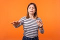 Portrait of blind young woman with brown hair in long sleeve striped shirt. indoor studio shot isolated on orange background