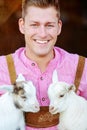 Blond bavarian man holding two little white goats Royalty Free Stock Photo