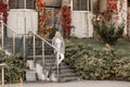 Portrait of blond beauteous woman walking stone stairs holding railing, expression after tour park, near building museum