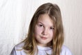 Portrait of blond beautiful girl 10 years old in front on light background, looking at camera, closeup Royalty Free Stock Photo