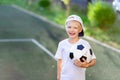 Portrait of a blond boy in a cap in a sports uniform with a soccer ball in his hands on the football field. Training Royalty Free Stock Photo