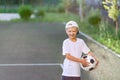 Portrait of a blond boy in a cap in a sports uniform with a soccer ball in his hands on the football field. Training Royalty Free Stock Photo