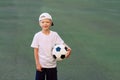 Portrait of a blond boy in a cap in a sports uniform with a soccer ball in his hands on the football field. Training Royalty Free Stock Photo