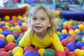 Portrait of a blond boy in a yellow t-shirt. The child smiles and plays in the children`s playroom. Ball pool