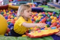 Portrait of a blond boy in a yellow t-shirt. The child smiles and plays in the children`s playroom. Ball pool Royalty Free Stock Photo