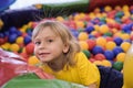 The child smiles and plays in the children`s playroom. Ball pool