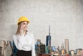 Portrait of a blond businesswoman wearing a yellow hard hat and talking on her smartphone. Royalty Free Stock Photo