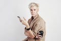 Portrait of blond caucasian woman angry anxious emotion drinks takeaway coffee, using smartphone on white background