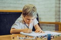 Portrait blond cute Preschool boy holding pen notebook look serious hard diligently diligently learn write, facial