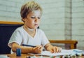 Portrait blond cute Preschool boy holding pen notebook look serious thoughtful think tired learn write, artistic facial