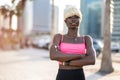 Portrait of blond haired black woman in sportswear with crossed arms posing on city street and looking at camera. Royalty Free Stock Photo