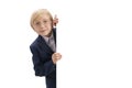 Portrait of blond little boy with white blank background. Boy with glasses and school uniform peeking out from behind board. Royalty Free Stock Photo