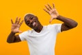 Portrait of a blond smiling charismatic african black man stalking hands to the sides in a white t-shirt on an orange