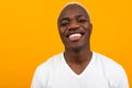 Portrait of a blond smiling charismatic african black man in a white t-shirt on an orange studio background