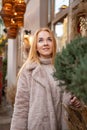 Portrait of a blond woman looking up on Christmas decorations background, festive street. Christmas mood. Holiday weekend Royalty Free Stock Photo