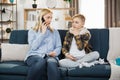 Portrait of blond woman mother with thermometer and smartphone calling to doctor at home. Royalty Free Stock Photo