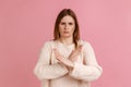 Woman standing with crossed hands, gesturing stop, showing symbol of rejection, body language.