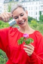 Blond woman watering with miniature can a flower