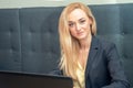 Portrait of blonde businesswoman is sitting in sofa and surfing on internet. Royalty Free Stock Photo