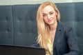 Portrait of blonde businesswoman is sitting in sofa and surfing on internet Royalty Free Stock Photo