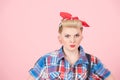 A Portrait of blonde curl pin-up girl with red head scarf. Stylish beautiful make-up on pink background. Concentrated female view