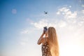 Portrait of a blonde girl in a floral print dress with a vintage video camera in a grape field records video of a plane taking off Royalty Free Stock Photo