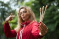 Portrait of blonde girl with hipster eyeglasses in dark red jacket holding a useful bamboo toothbrushes outdoors in the Royalty Free Stock Photo