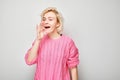 Portrait of blonde girl shouting loudly with hands, news, palms folded like megaphone Royalty Free Stock Photo