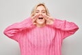 Portrait of blonde girl shouting loudly with hands, news, palms folded like megaphone Royalty Free Stock Photo